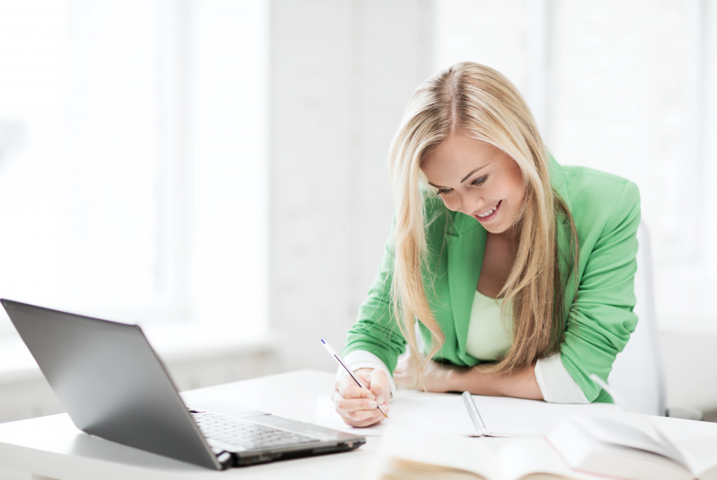 education concept - picture of smiling student girl writing in notebook
