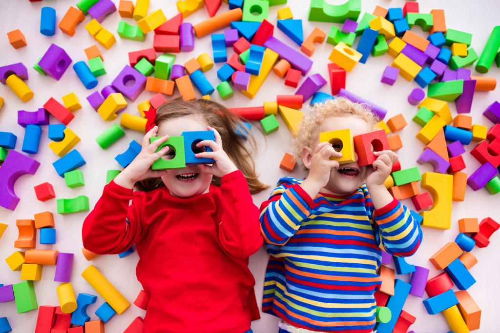 Happy preschool age children play with colorful plastic toy blocks