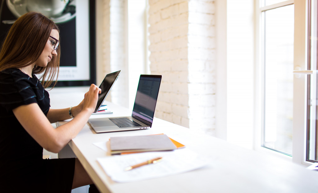 A Woman Using a Tablet and a Laptop