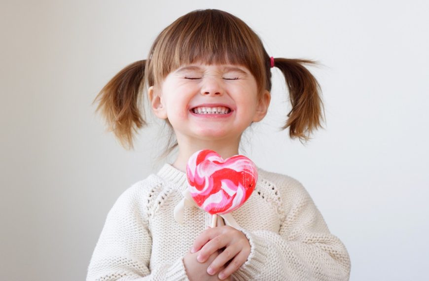 happy toddler holding a lollipop